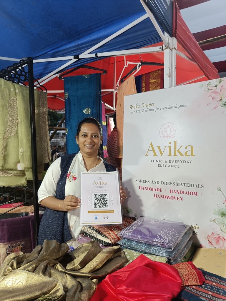 Avika stall owner holding a ReviewLoop QR flyer with sarees and dress materials
