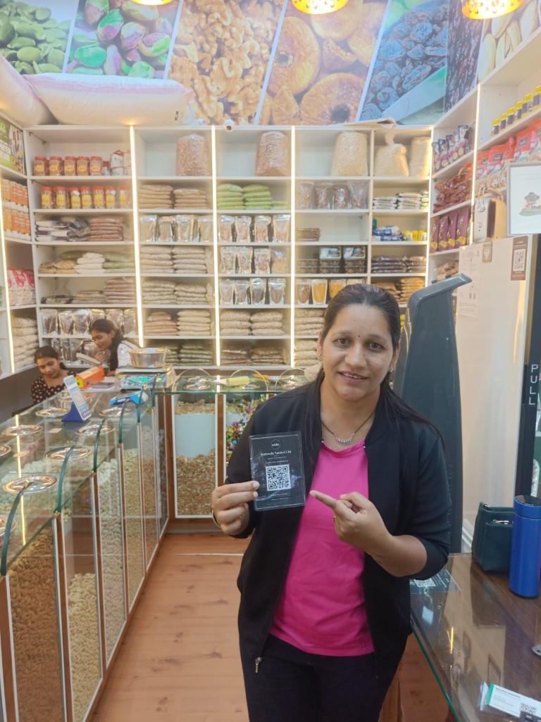 Dry fruits shop staff with ReviewLoop QR standee at the counter