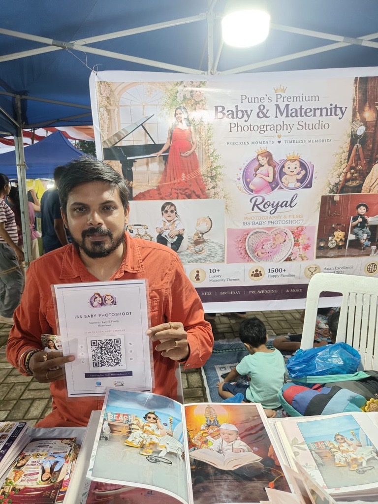 IBS Baby Photoshoot photographer holding a ReviewLoop QR flyer at a market stall