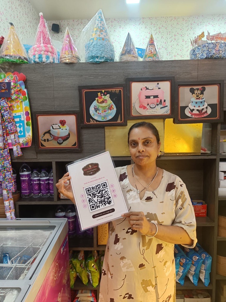 Lata's Baker's House staff holding a ReviewLoop QR flyer in the cake shop