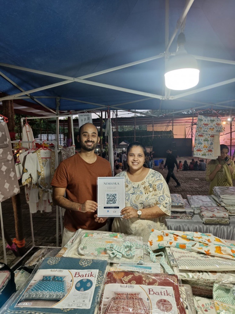 Nimiora home decor stall with a ReviewLoop QR flyer at a market counter