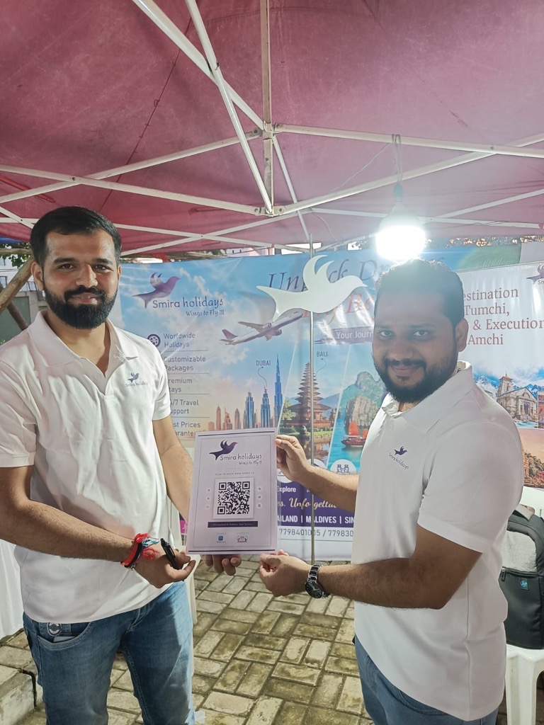 Smira Holidays travel planners holding a ReviewLoop QR flyer at their stall